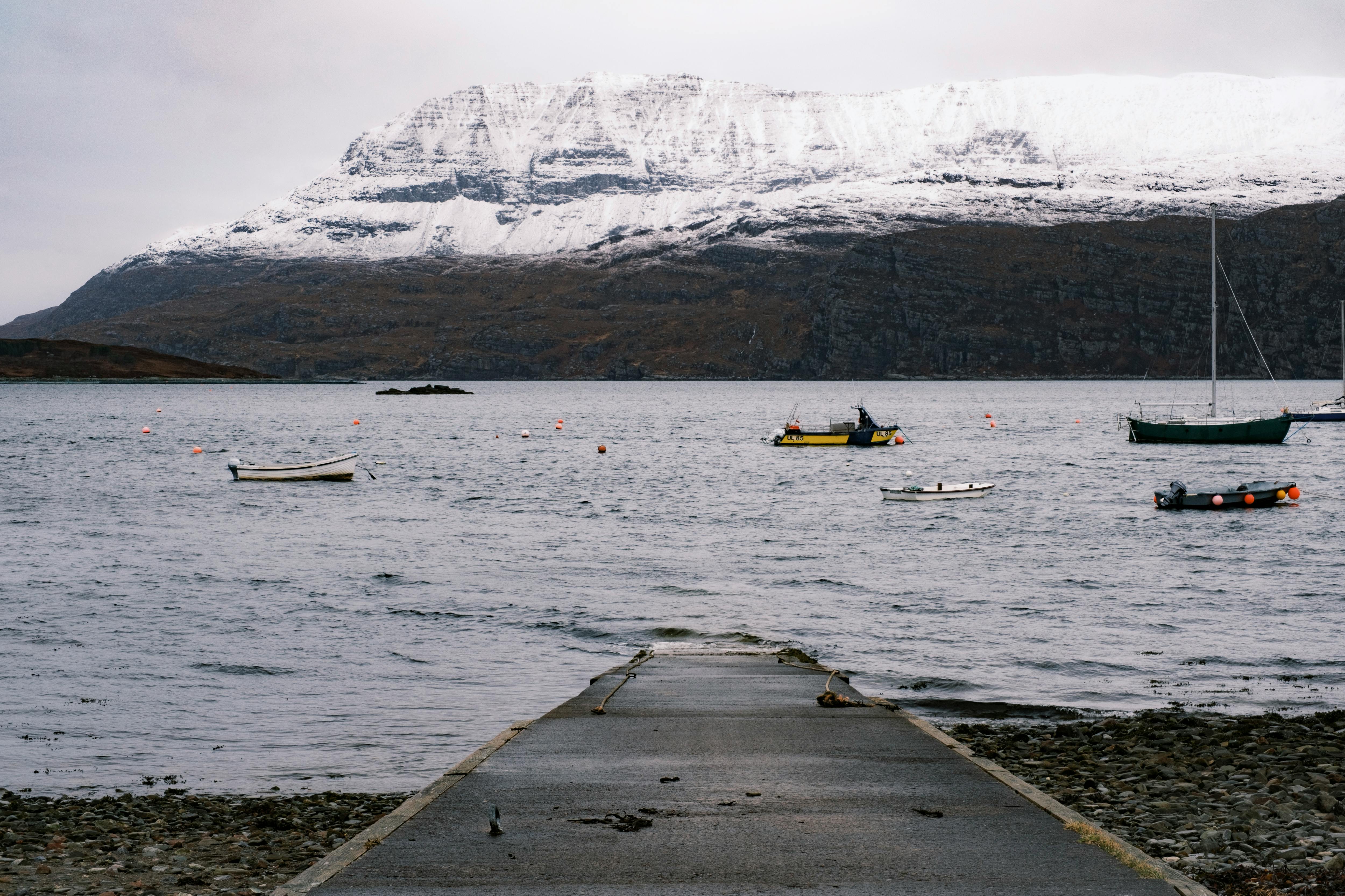 Prescription Goggle Inserts - Tranquil lake scene with snow-capped mountains and moored boats.