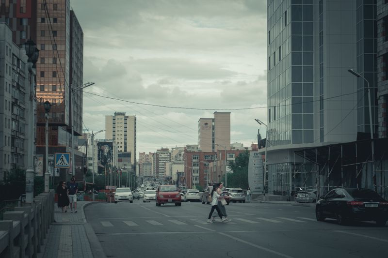 A lively day in the city with pedestrians crossing streets surrounded by modern architecture.