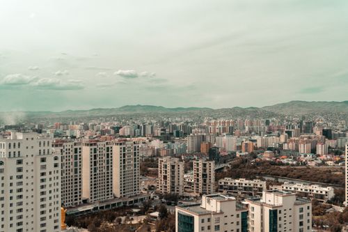 Free Aerial view of a vast cityscape featuring modern apartment buildings and distant hills under a cloudy sky. Stock Photo