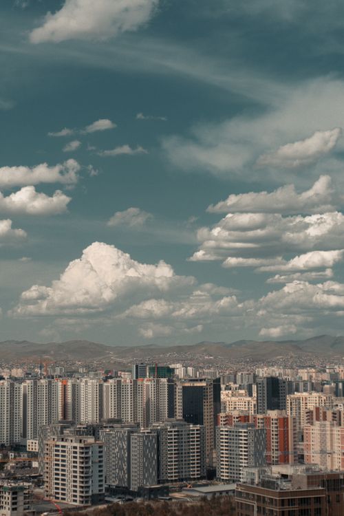 Free Aerial view of a modern city skyline with skyscrapers under a dramatic sky, showcasing urban architecture. Stock Photo