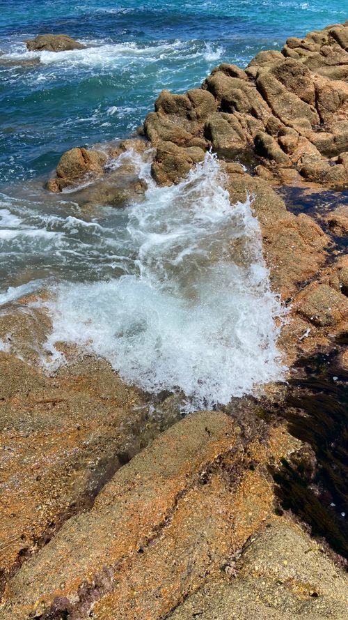 Free Sunlit rocky shore with crashing waves in A Coruña, Spain, showcasing nature's eroded beauty. Stock Photo