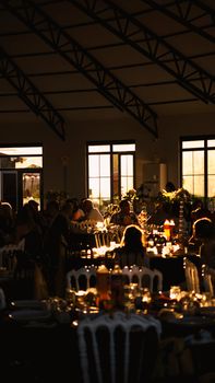 An intimate indoor setting featuring beautifully set tables under warm lighting during a sunset gathering.