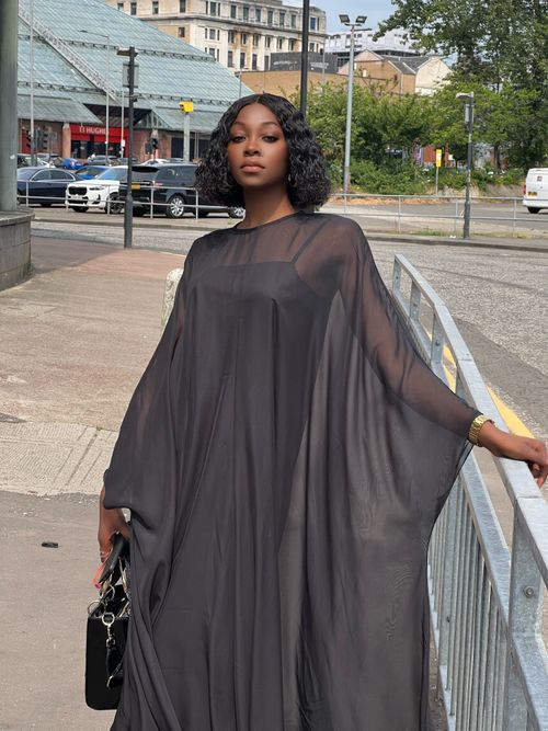 Free A stylish black woman poses elegantly in a black dress on the streets of Glasgow, Scotland. Stock Photo