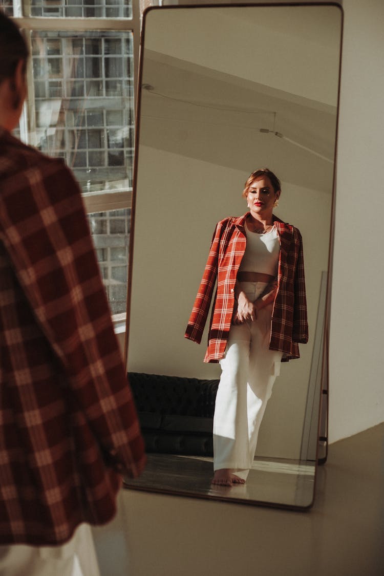 Young Woman Looking At Her Reflection In A Full Length Mirror 