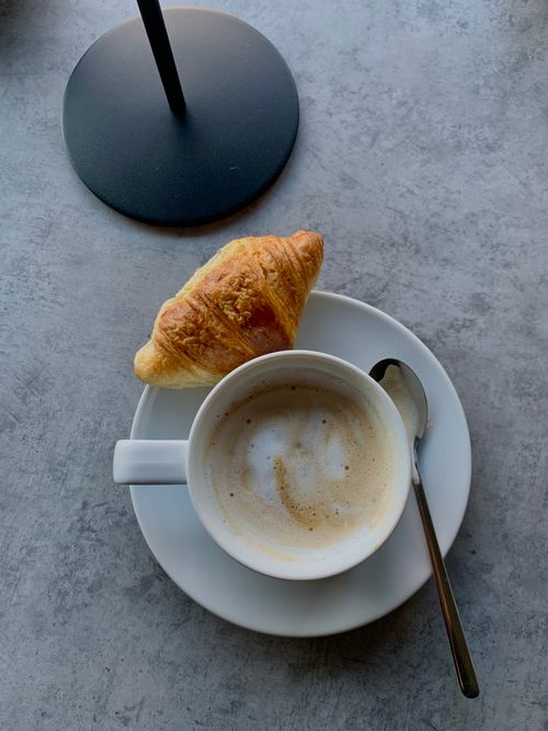 Free Top view of a coffee cup and croissant on a plate, perfect morning setup. Stock Photo