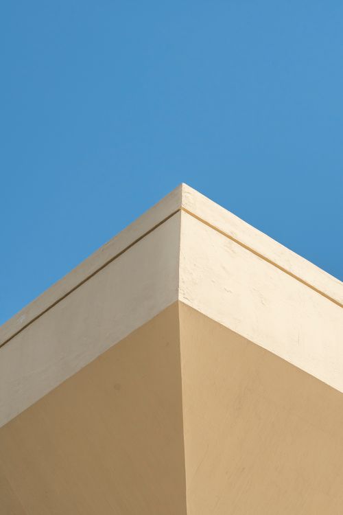 Free A minimalist architectural design featuring a beige corner against a clear blue sky in Dubai. Stock Photo