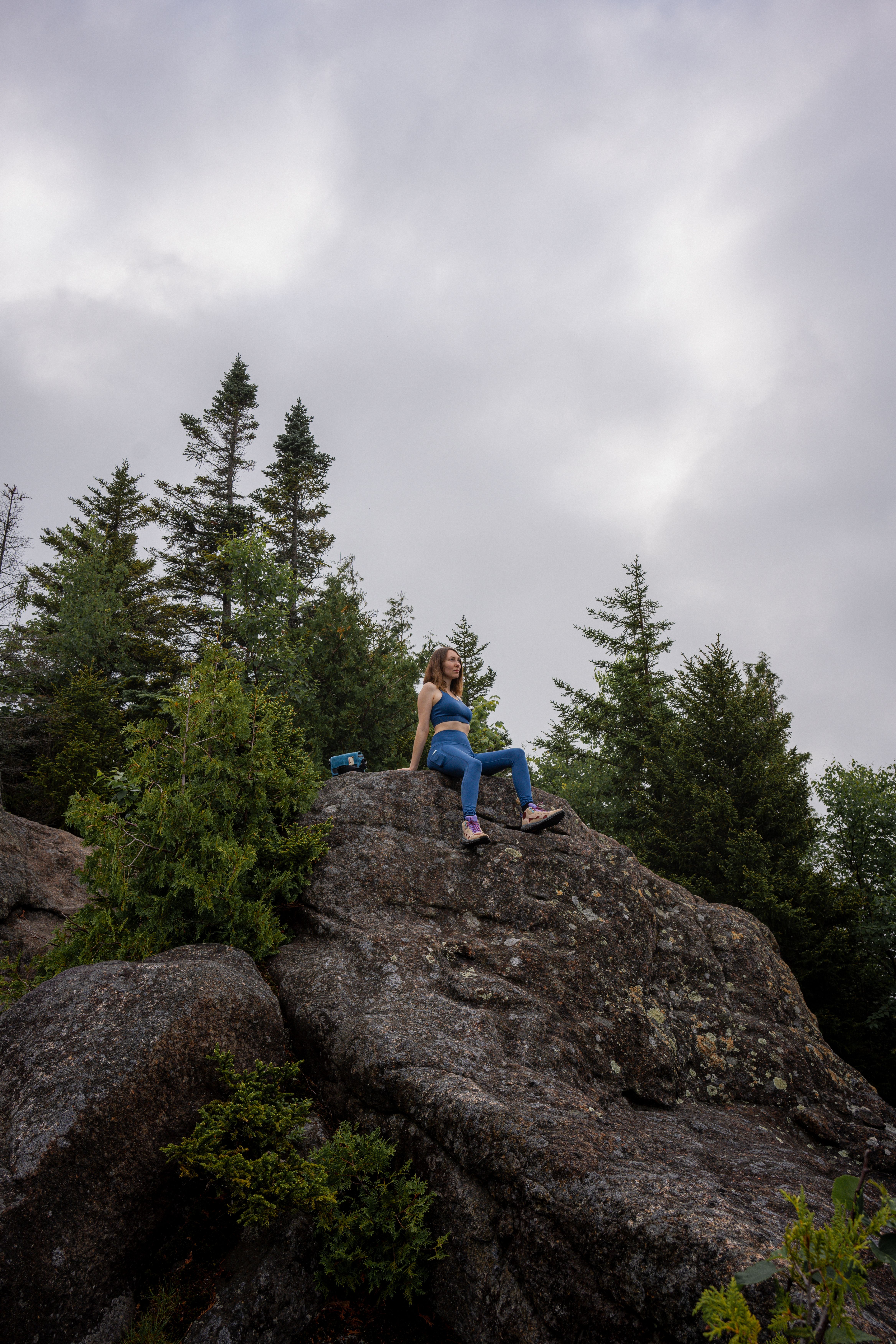Woman in Blue Top Sitting on Cliff Rock · Free Stock Photo