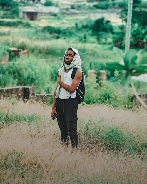 Man with a Sweatshirt Wrapped around his Head Standing in Grass