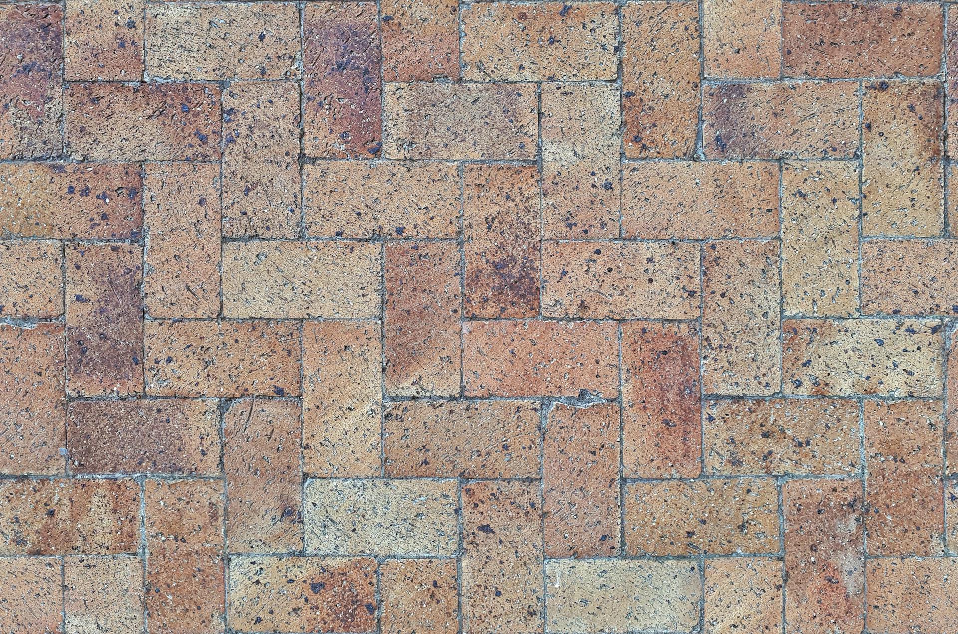 Close-up of textured brick paver pattern in a herringbone layout.