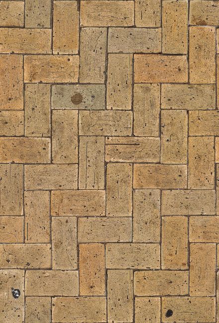 An overhead view of a rustic brick pavement with a classic herringbone pattern.