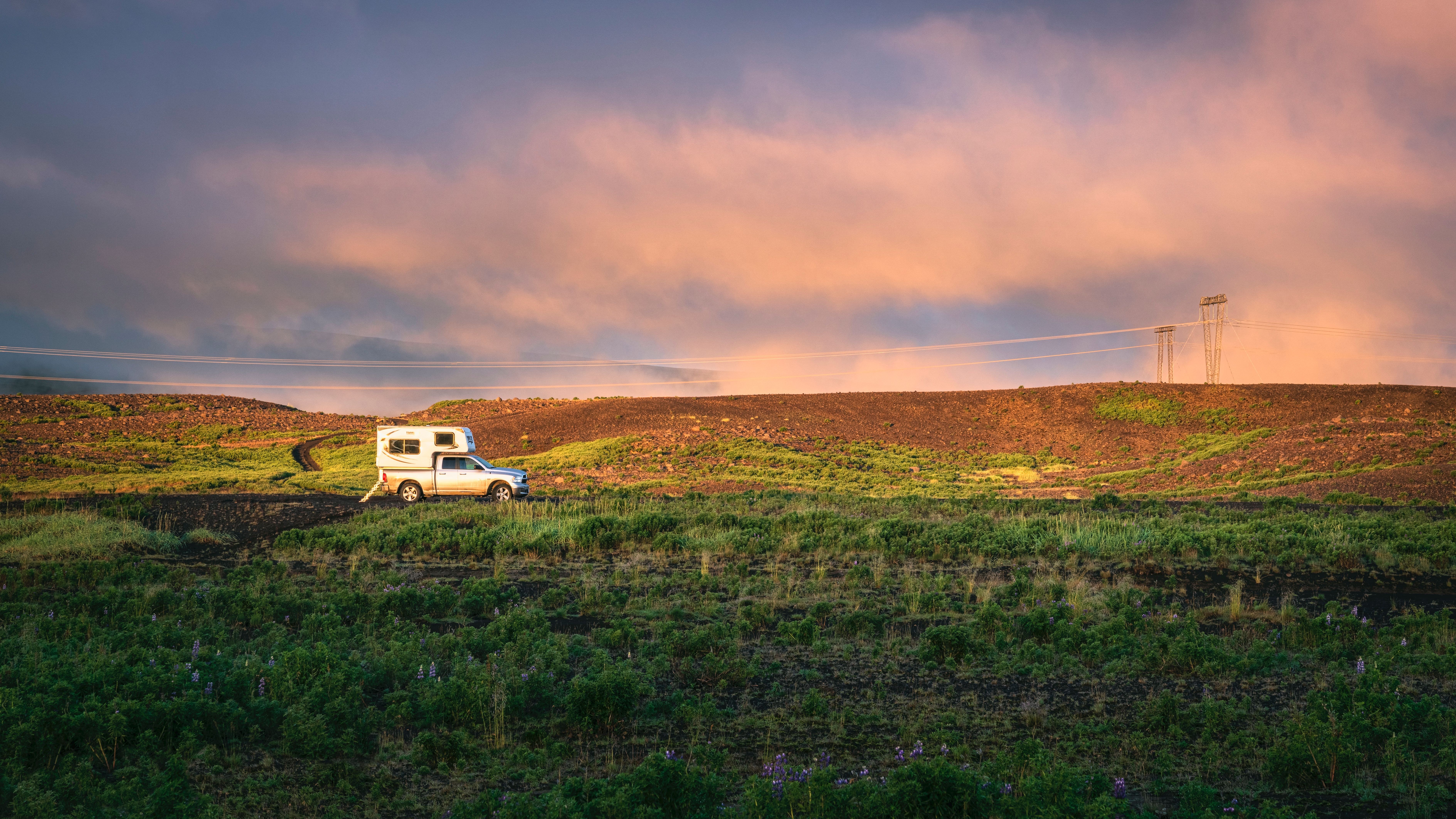 An RV travels through the scenic countryside of Reykjavík at sunset in summer.