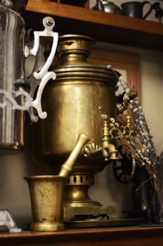Close-up of a vintage brass samovar alongside a pestle indoors.