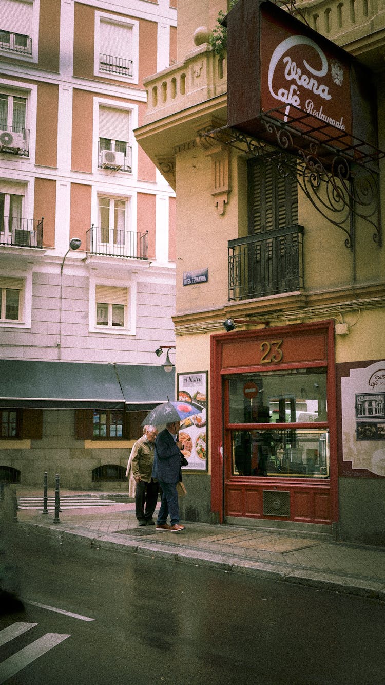 People Near Building On Street Corner In Rain