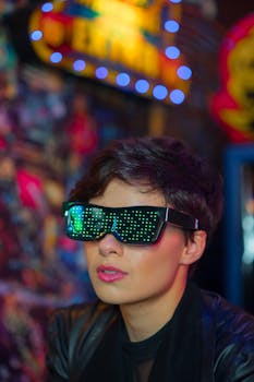 Modern portrait of a woman wearing LED sunglasses under neon lights.