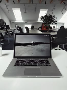 A sleek laptop on a pristine desk in a contemporary open office space.