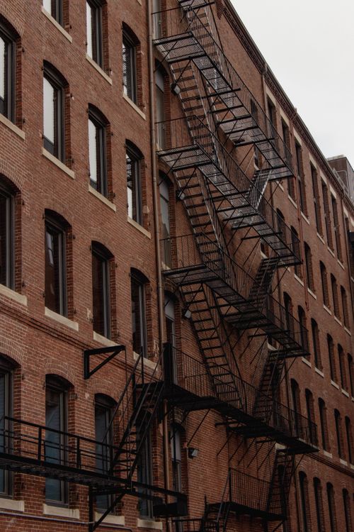 Free Brick building with metal fire escape stairs in urban setting, vertical view. Stock Photo