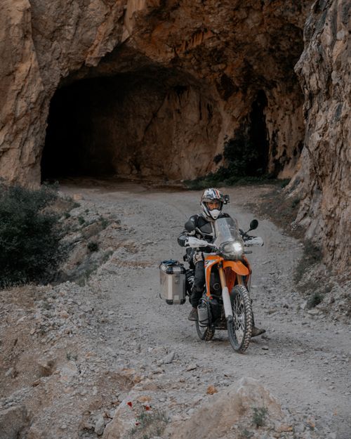 Free Rider navigating rocky cave on an adventure motorcycle, exploring natural landscapes. Stock Photo