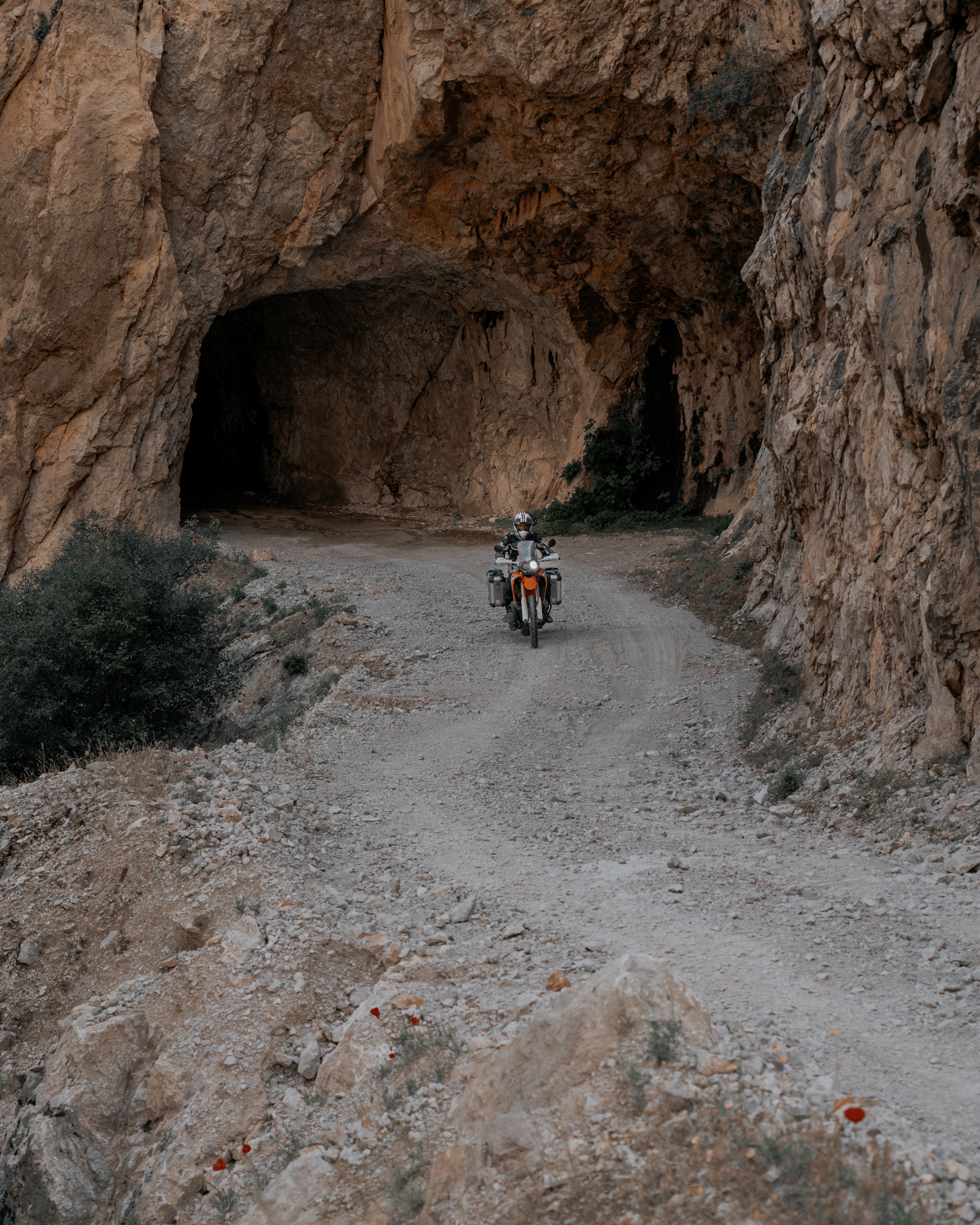 Motorcyclist navigating a rocky tunnel on a dirt road, showcasing adventure.