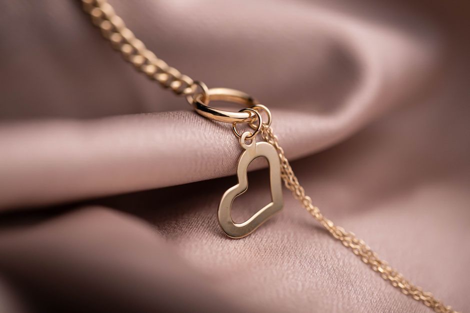 A gold heart pendant and fine chain on blush satin