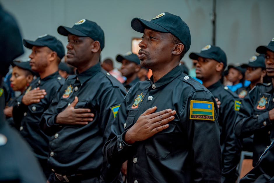 A group of Rwandan police officers in uniform taking an oath during a formal ceremony indoors.