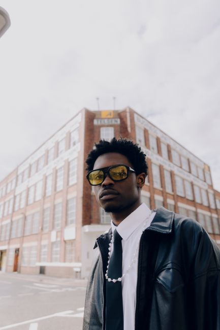 Portrait of a fashionable man with yellow tinted glasses in an urban setting.