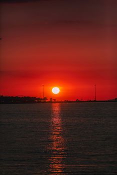 Stunning red sunset casting a reflective glow over tranquil water surface.