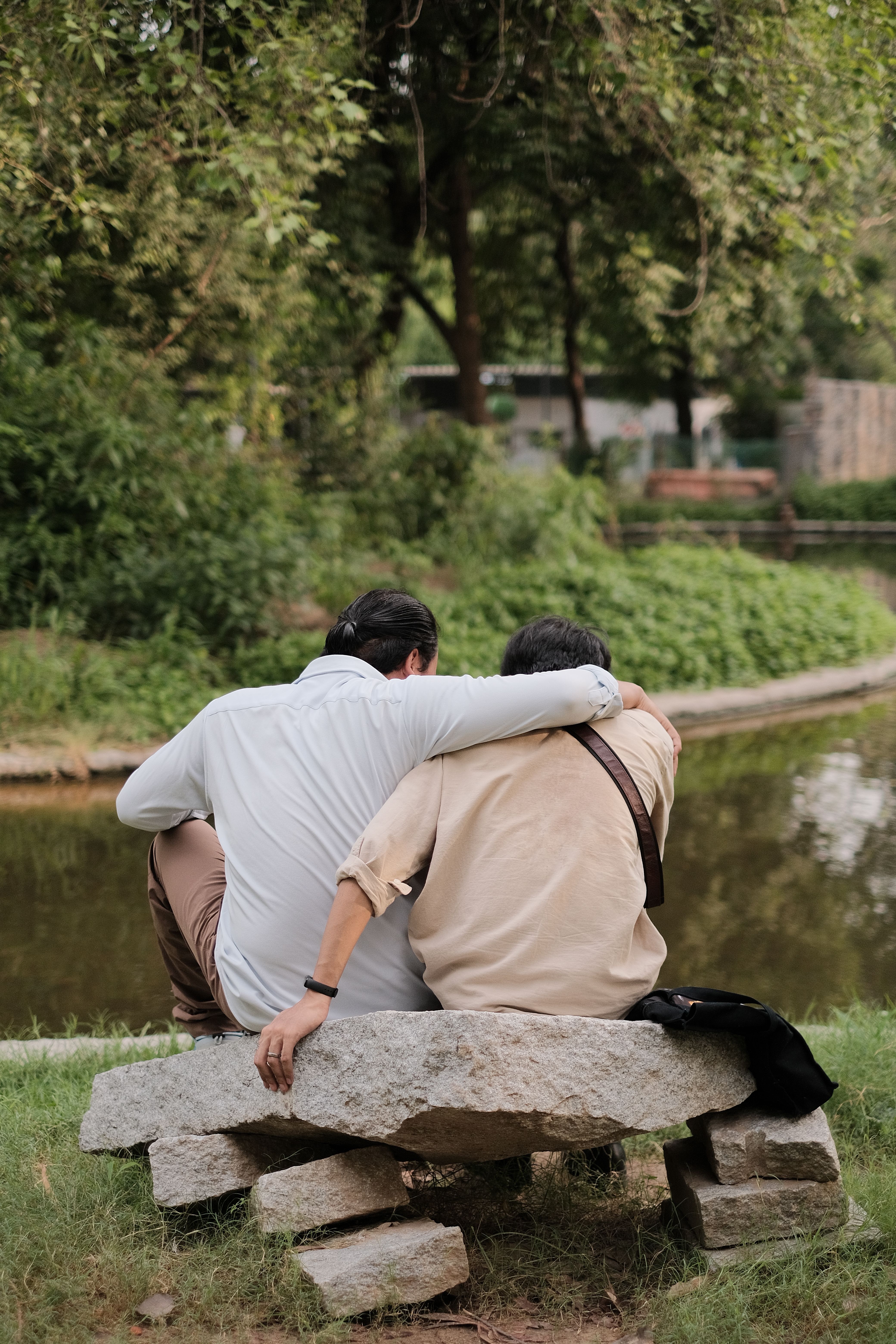 Back View of Men Sitting on Stone by River at Park · Free Stock Photo