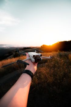 A hand holding a drone against a vivid sunset backdrop, symbolizing technology and adventure.