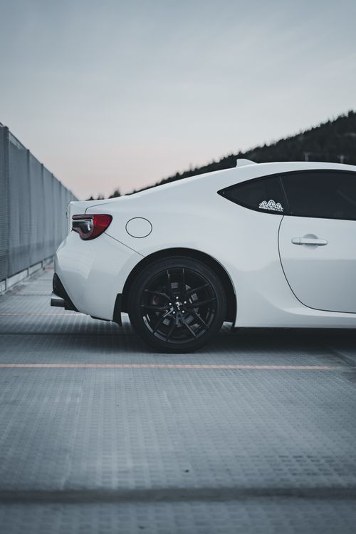 Free Close-up of a white sports car parked on an outdoor lot at sunset. Stock Photo