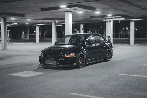 Free A stylish black sports car parked in a dimly lit urban parking garage at night. Stock Photo