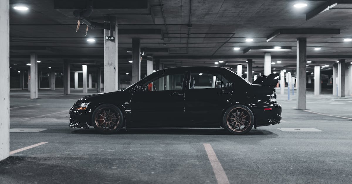 A sleek black Mitsubishi Lancer Evolution parked in an empty urban parking lot at night.