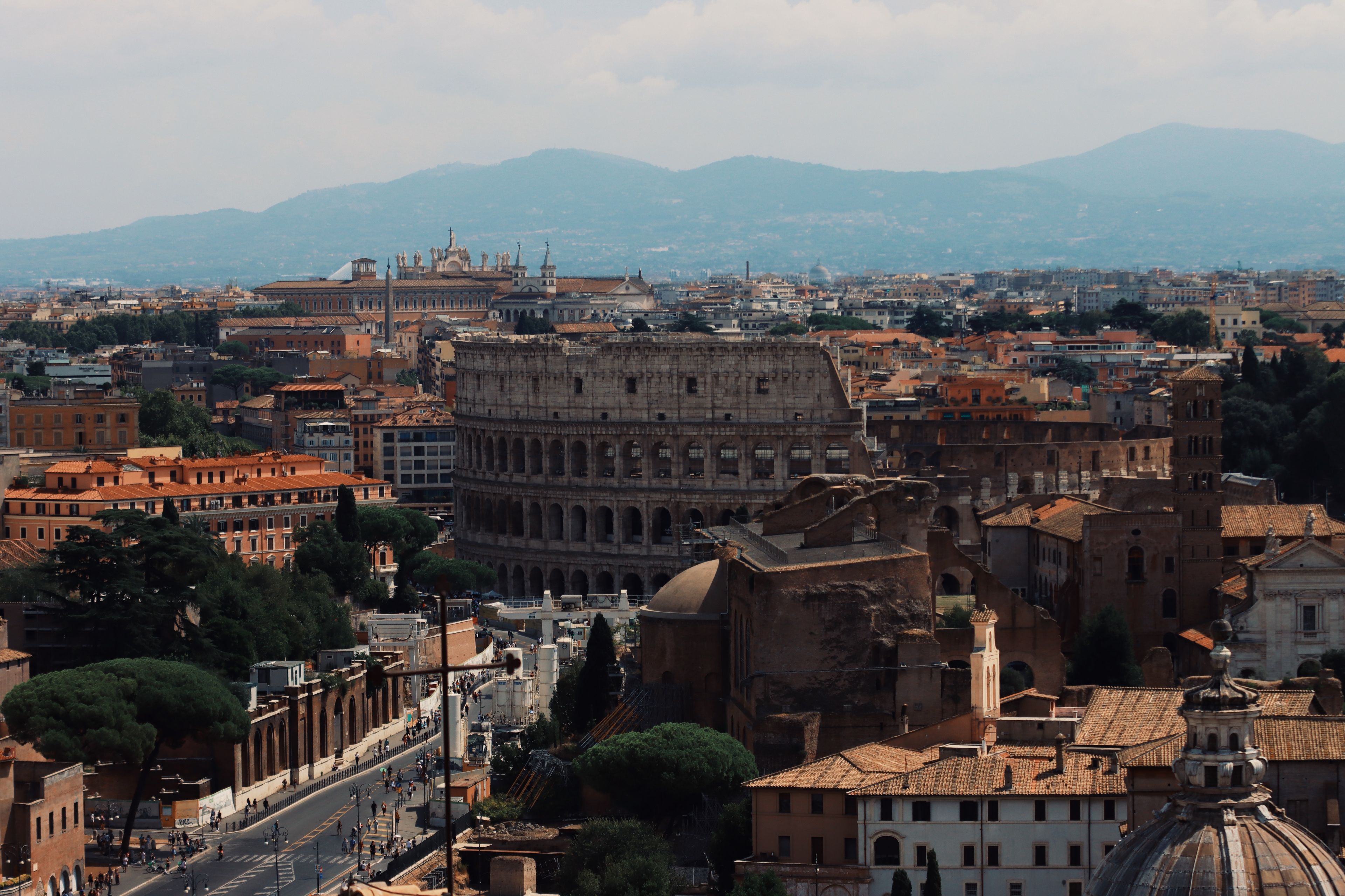 Drone shot of the iconic Colosseum and surrounding cityscape in Rome, Italy.