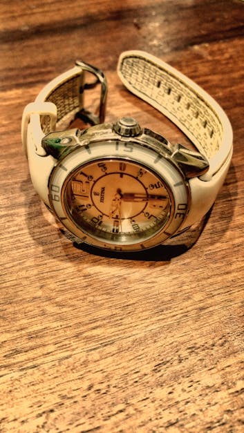 Round Silver-colored and White Analog Watch With White Rubber Band on Brown Wooden Surface