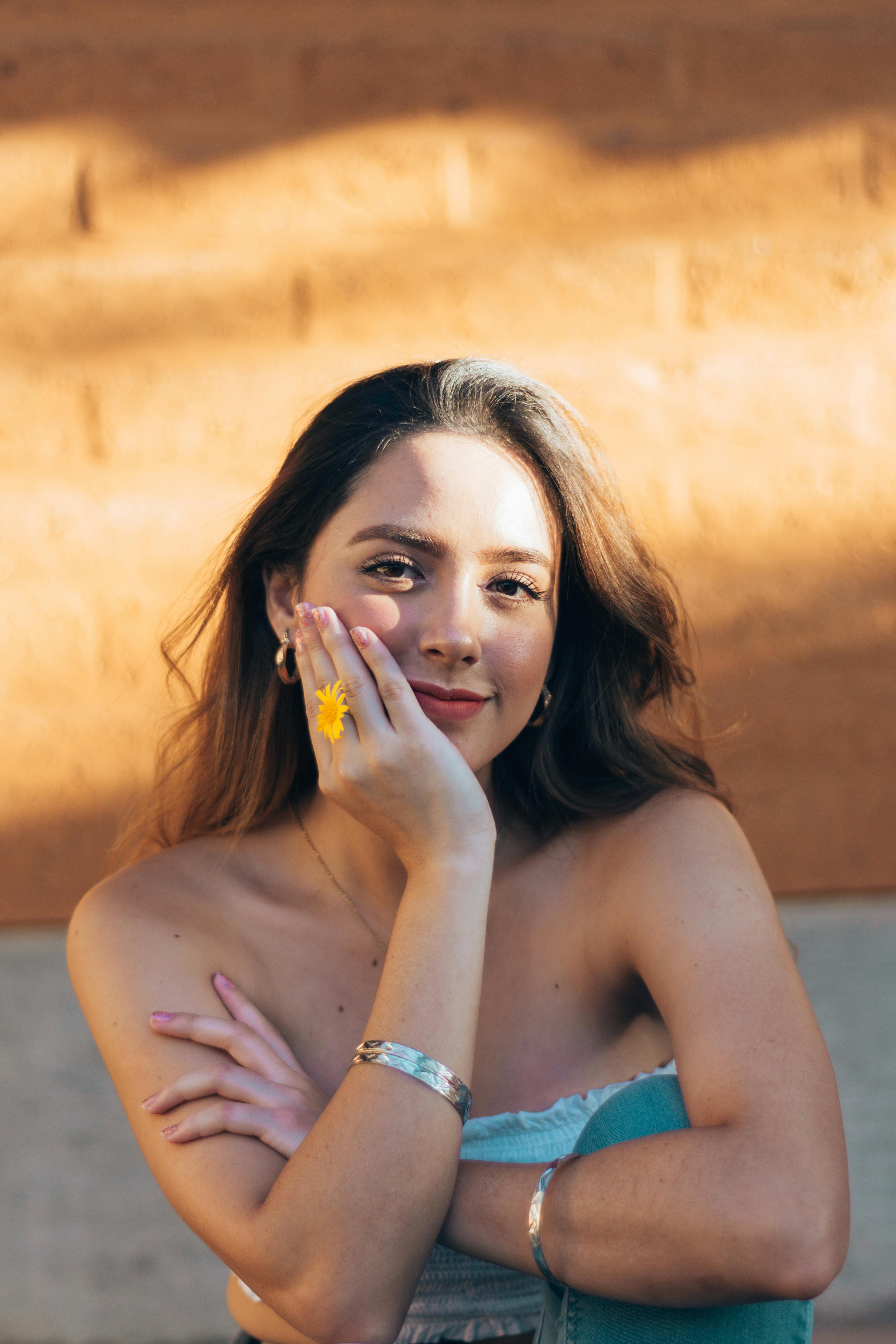 Sunlit portrait of a smiling woman with a yellow flower in Oaxaca, Mexico.