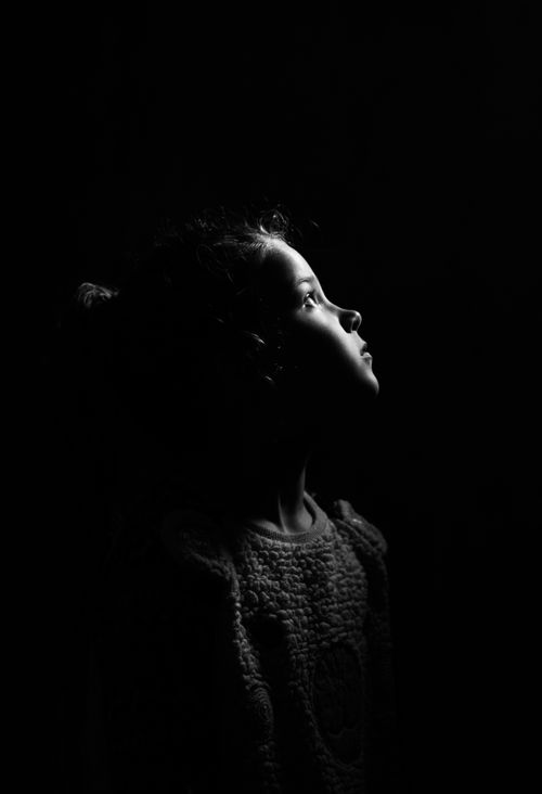 Free A dramatic black and white portrait capturing a young girl looking upward, lost in thought. Stock Photo