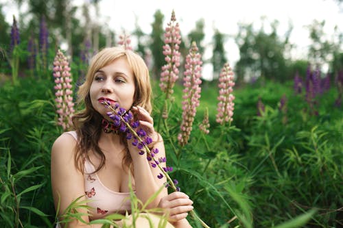 Young Woman Sitting on a Field between Flowers