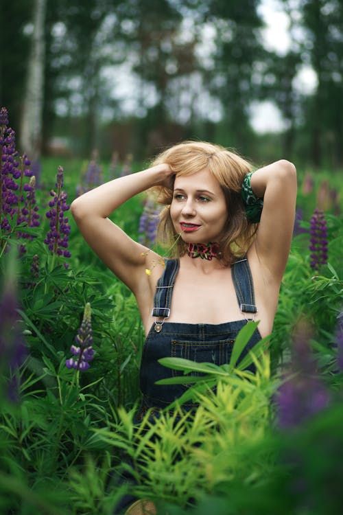 Young Woman Standing on a Field between Flowers