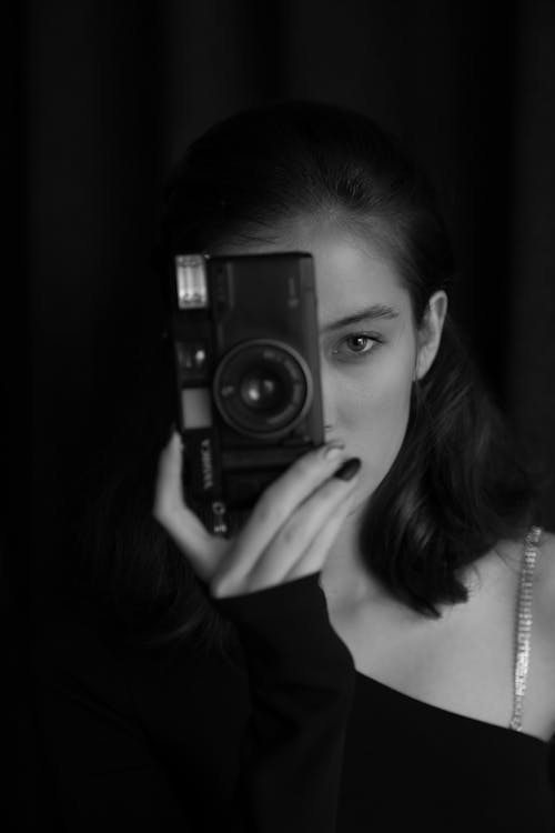 Free A woman holding up a camera in black and white Stock Photo