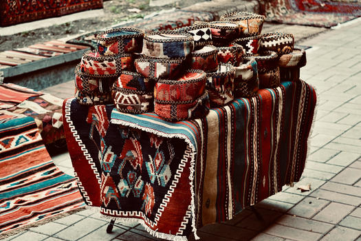 Colorful woven baskets and rugs displayed at an outdoor market stall.