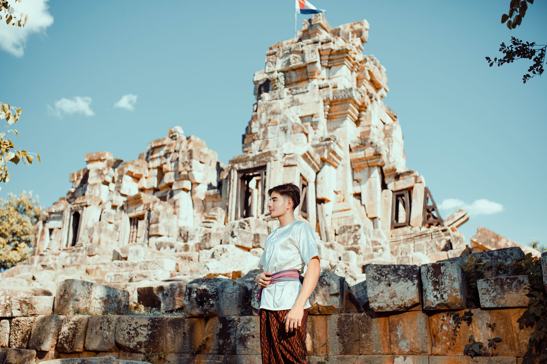 Young man in traditional clothing stands by Cambodia's ancient ruins under a clear sky.. Photo by HANUMAN PHOTO STUDIO🏕️📸 on Pexels