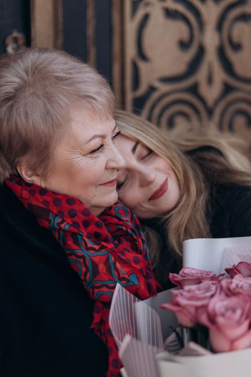 Free A touching portrait of a mother and daughter embracing with flowers, showcasing love and joy. Stock Photo