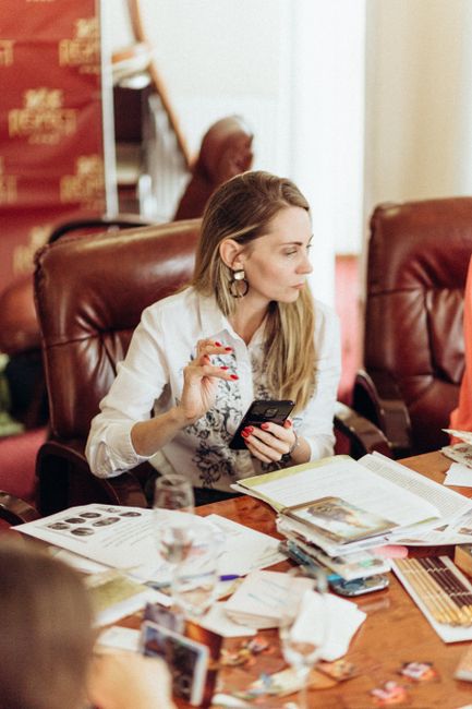 Focused woman strategizing at a conference table with cellphone and documents.