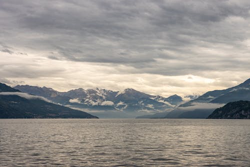 View of a Body of Water and Mountains under a Cloudy Sky 