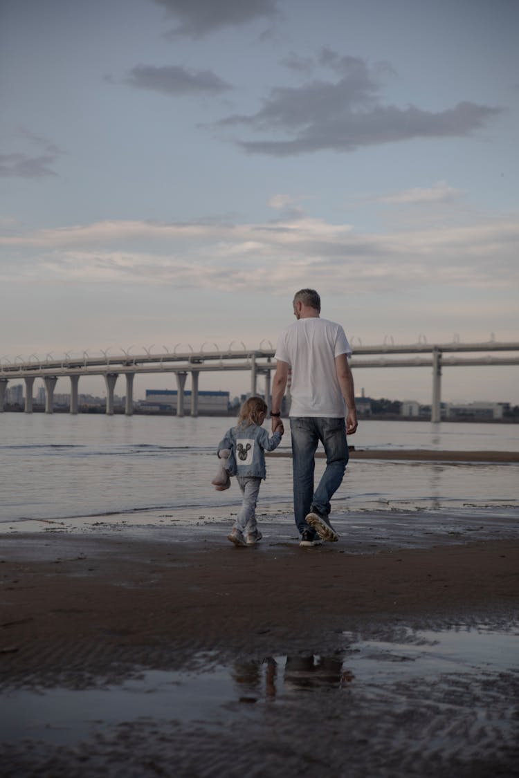 Father Walking With Daughter On Beach