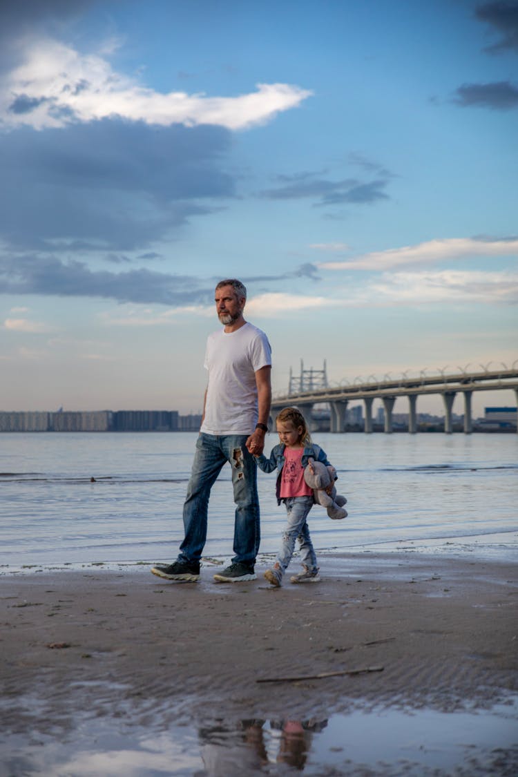 Father Walking With Daughter On Beach