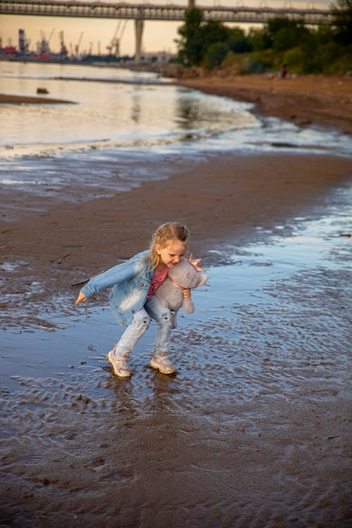 Little Girl Jumping in the Puddles on the Beach 