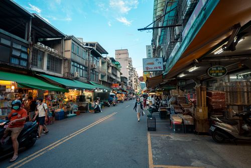 Free Bustling street market scene in Taipei showcasing diverse stalls, shoppers and urban architecture. Stock Photo