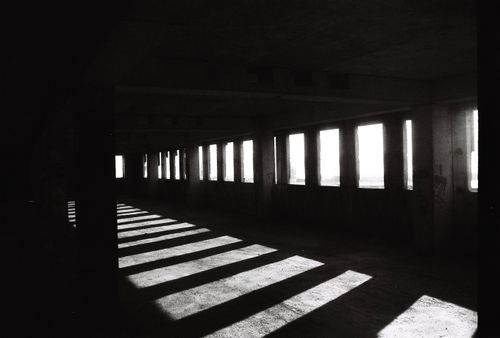 Free Black and white photo of sunlit shadows in a dark, empty abandoned building. Stock Photo