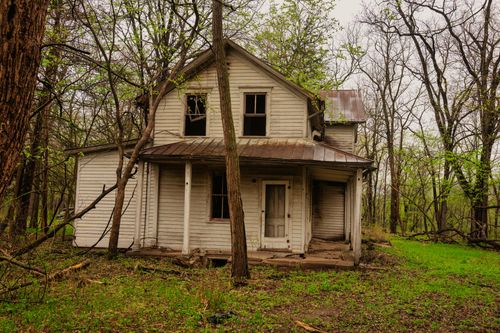 Free A weathered, abandoned house surrounded by dense trees in West Newton, MN. Stock Photo