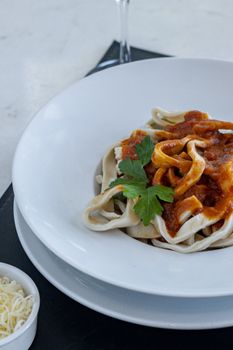 A close-up of homemade pasta topped with rich tomato sauce and garnished with fresh herbs.